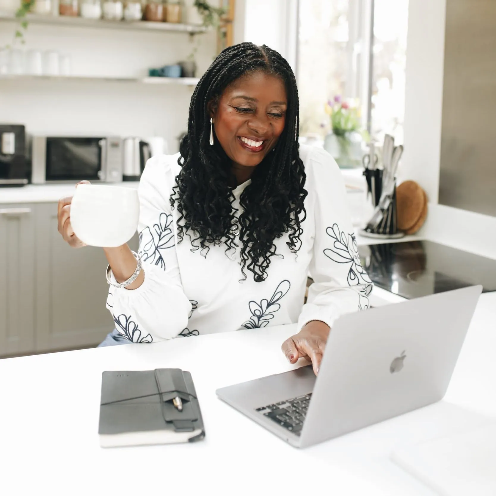 Lorraine Lee at a kitchen table with a laptop and a cup of tea